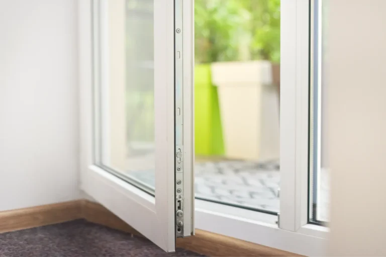 Close-up of white sliding door track with plant in background